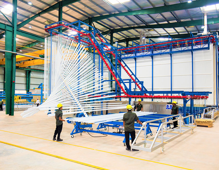 Factory workers handling aluminium profiles in a production line